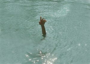 A person stretching a hand out of the water, possibly drowning